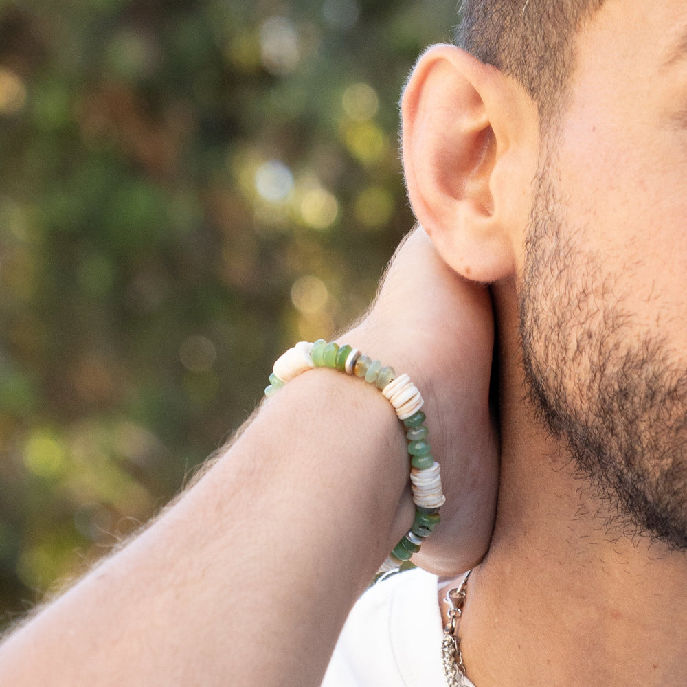 Close-up of a person wearing a bracelet with a blurred natural background
