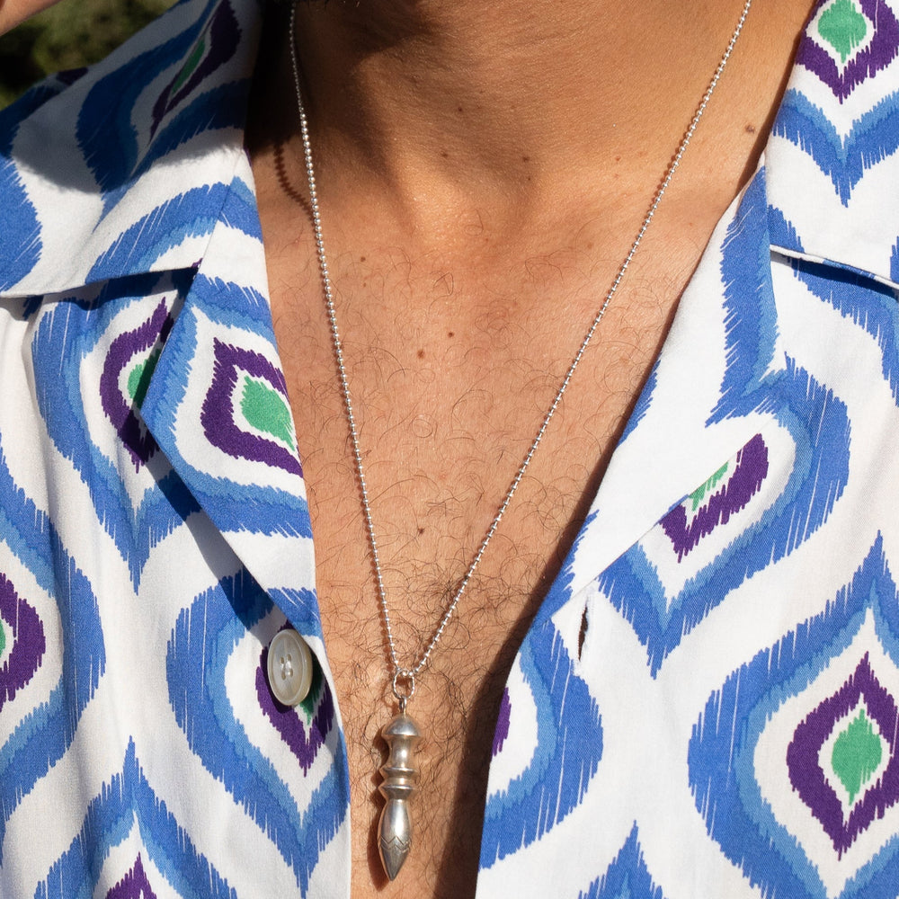 Person wearing a silver necklace with a patterned shirt