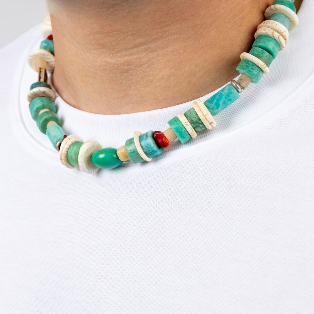 Necklace with green and beige beads worn by a person on a white background