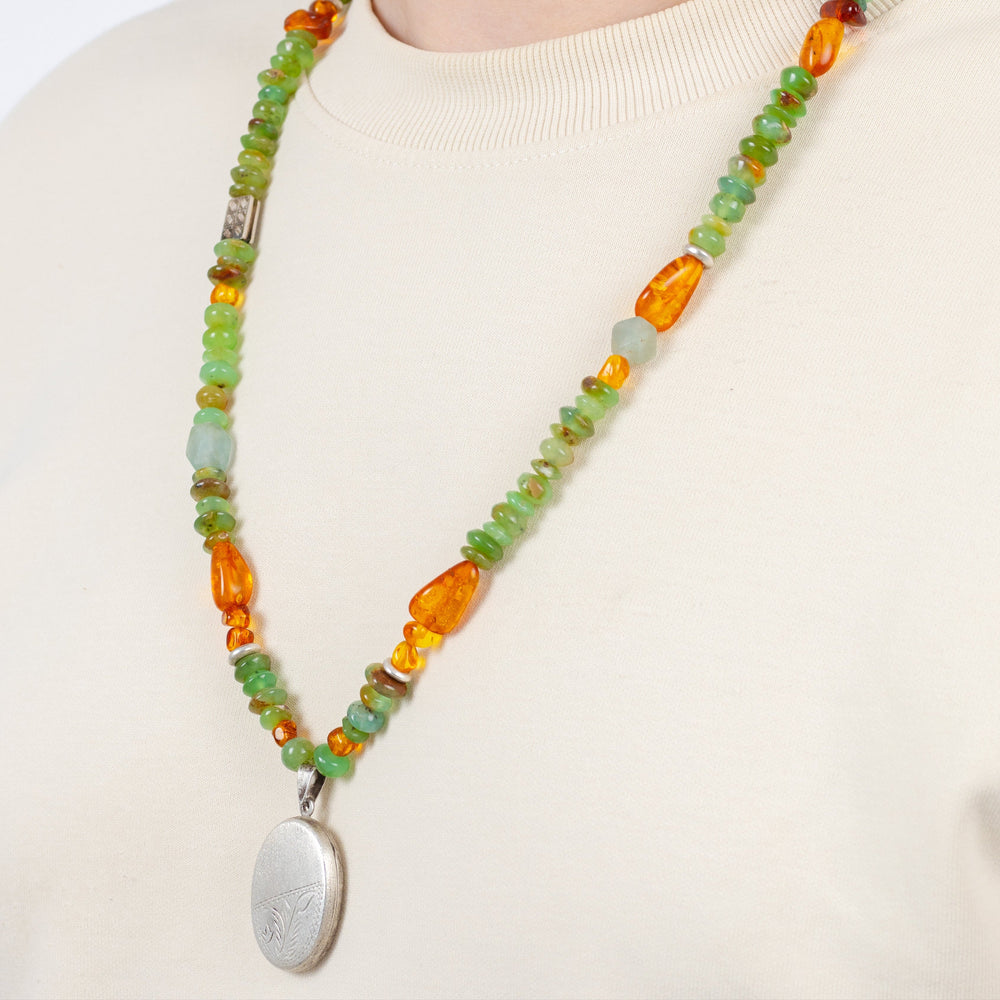 Necklace with multicolored beads and a silver pendant on a plain background