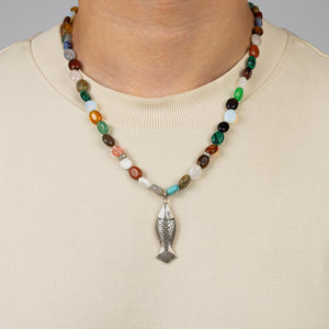 Necklace with a fish pendant worn by a person on a plain background