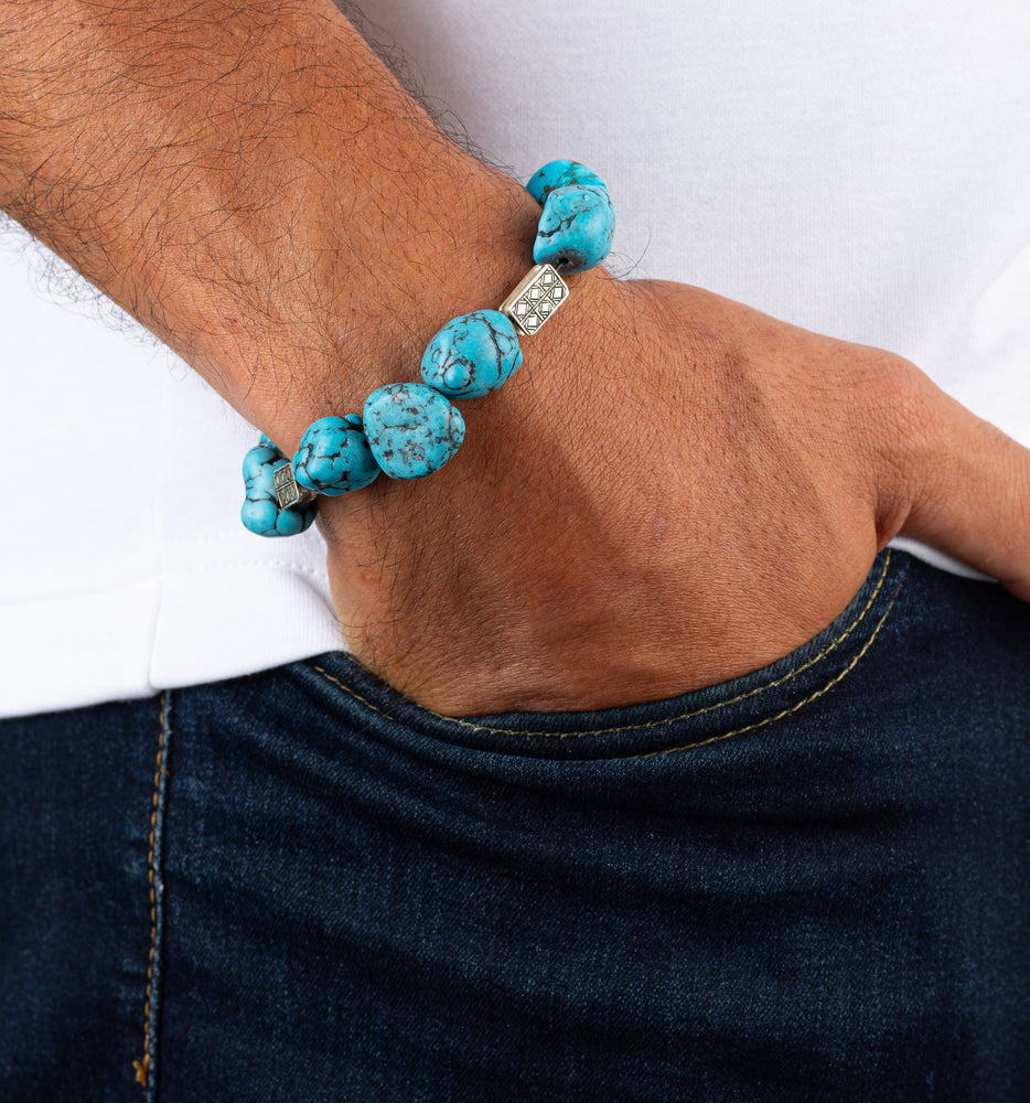 Turquoise beaded bracelet on a wrist with a white shirt and dark jeans.