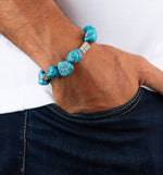 Turquoise beaded bracelet on a wrist with a white shirt and dark jeans.