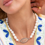 Pearl necklace with a silver clasp worn by a person against a colorful background