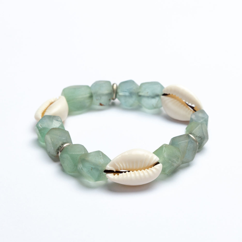 Green beaded bracelet with cowrie shells on a white background