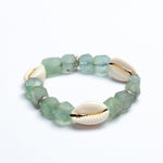 Green beaded bracelet with cowrie shells on a white background