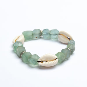 Green beaded bracelet with cowrie shells on a white background