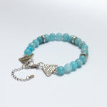 Turquoise beaded bracelet with silver charms on a white background