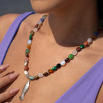 Close-up of a colorful beaded necklace with a fish pendant worn by a person.