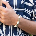Close-up of a wrist wearing a bracelet with a patterned garment in the background