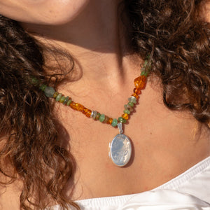 Close-up of a person wearing a colorful beaded necklace with a pendant.
