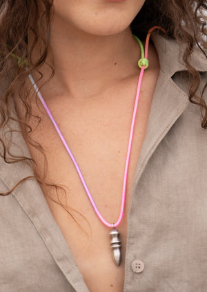 Necklace with a pink cord and silver pendant worn by a person