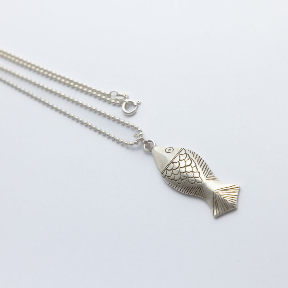 Silver fish-shaped pendant on a chain against a white background